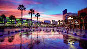 Palm trees and parking barricades in front of a modern looking shopping area at sunset 